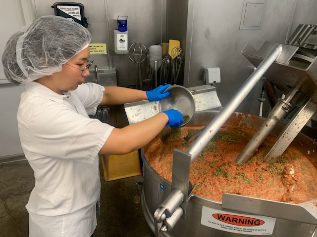 A student pours ingredients into an industrial-sized mixer.