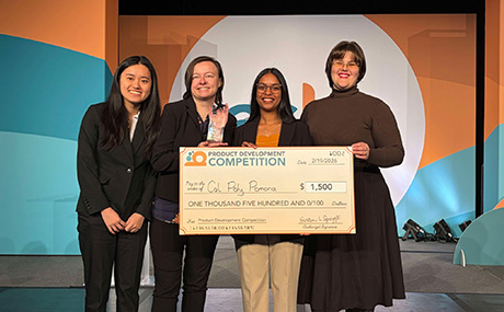 Four women posing with a replica check.
