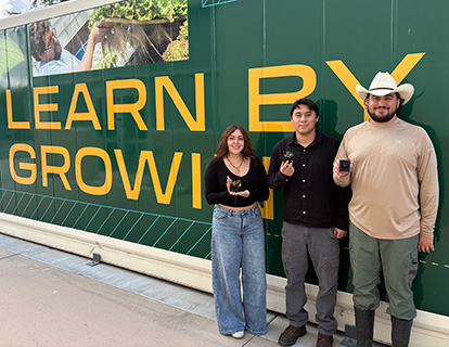 The three students pose by the Cal Poly Pomona vertical farm.