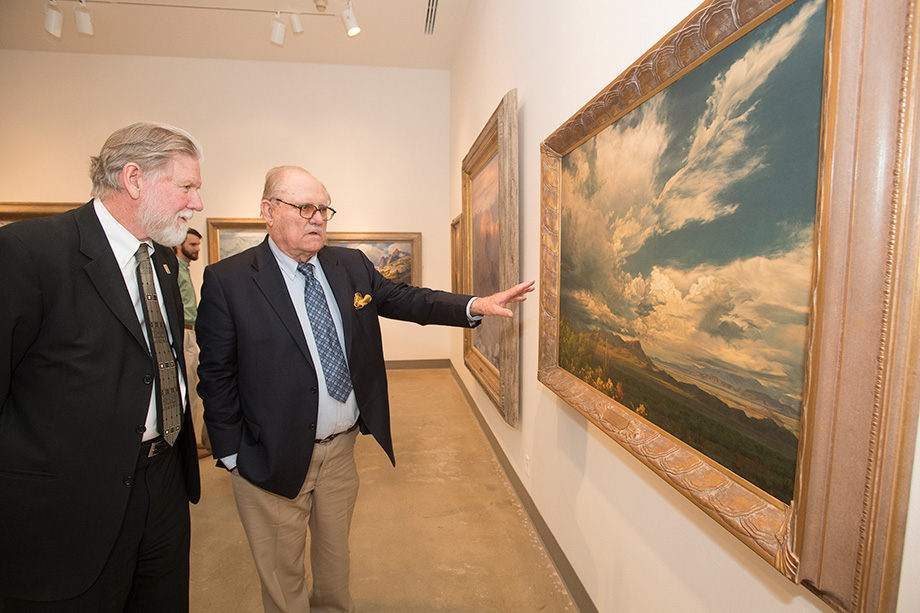 Don B. Huntley showing a guest a painting in his gallery on campus.