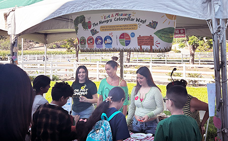 Schoolchildren crowd around a booth about nutrition. 