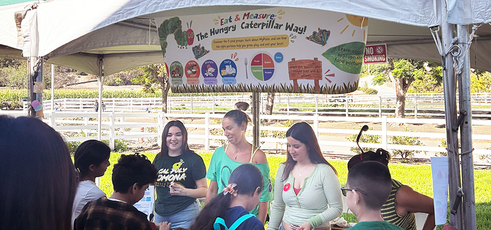 Schoolchildren crowd around a booth to learn about nutrition.