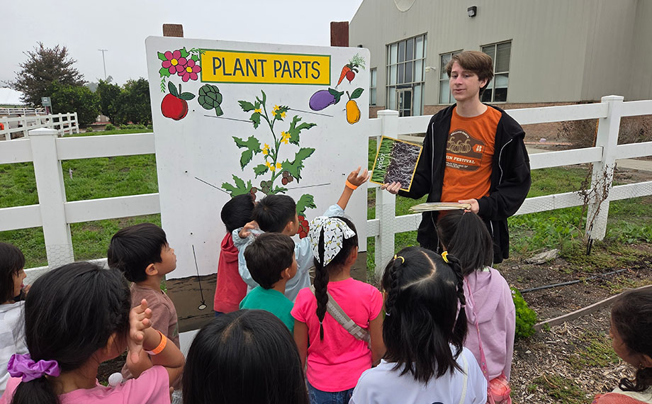 A student teaches schoolchildren about plants.