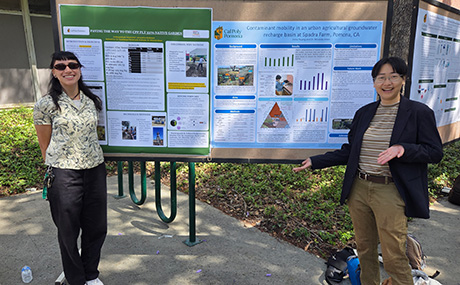 Two students pose in front of their poster displays.