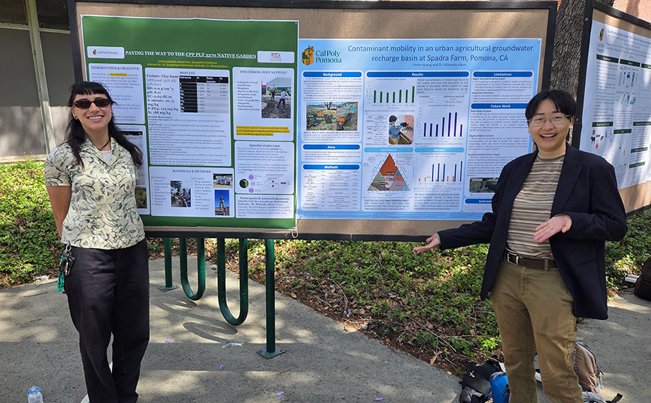Two students pose in front of their poster displays. 