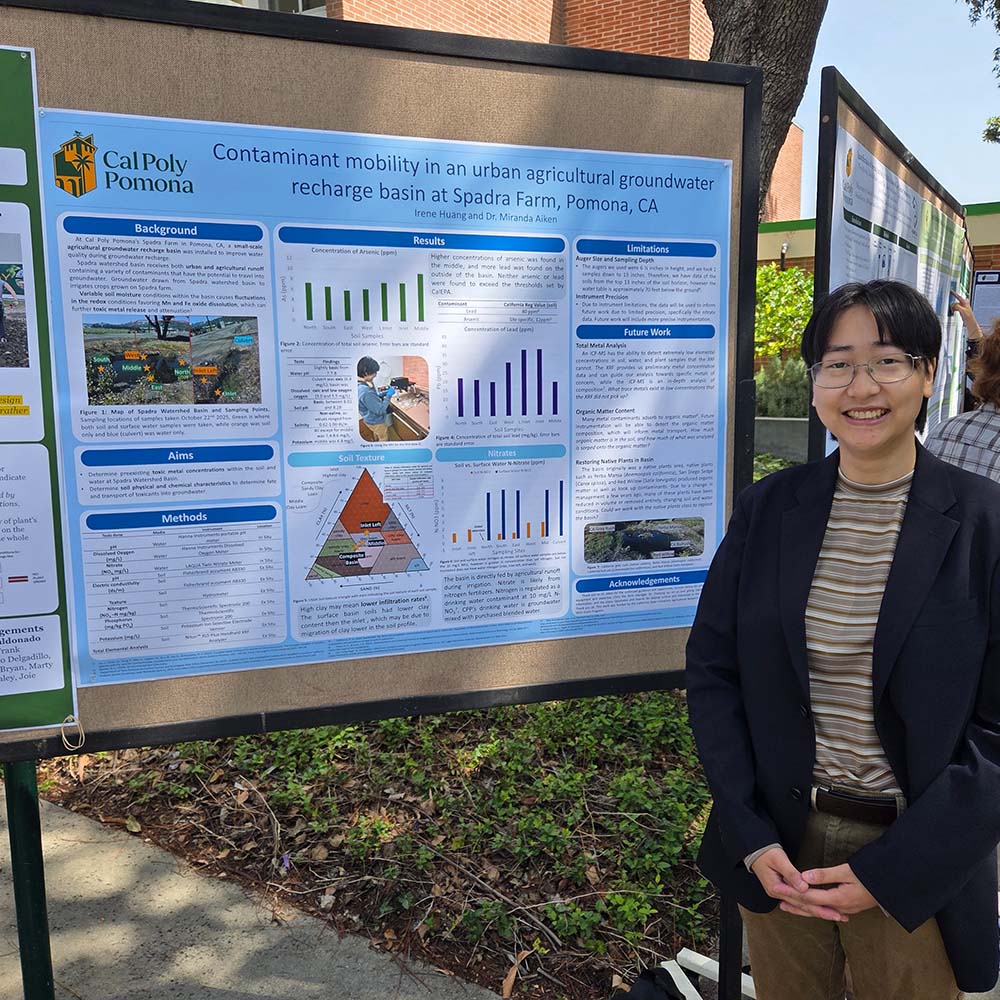 A student smiles as she stands in front of her poster presentation on contaminant mobility in urban ag groundwater at Spadra Farm.