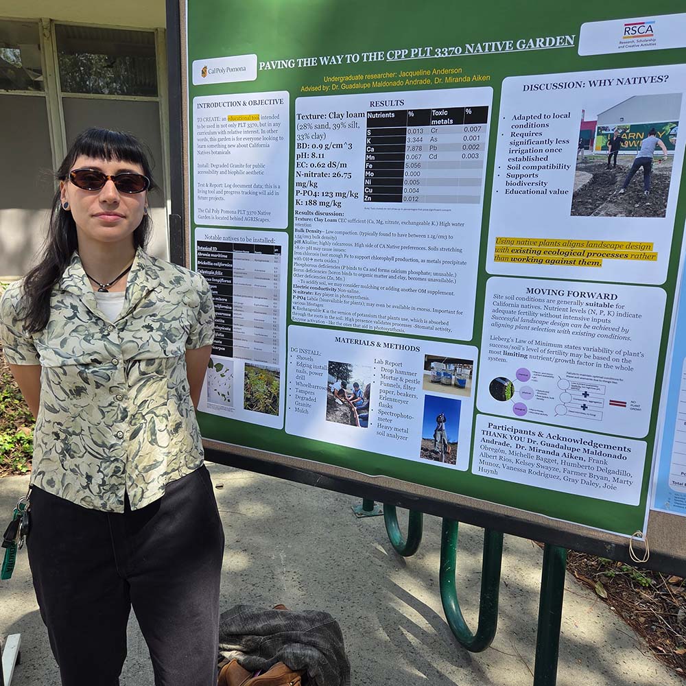 A female student with sunglasses poses in front of her presentation about creating a native plant garden.