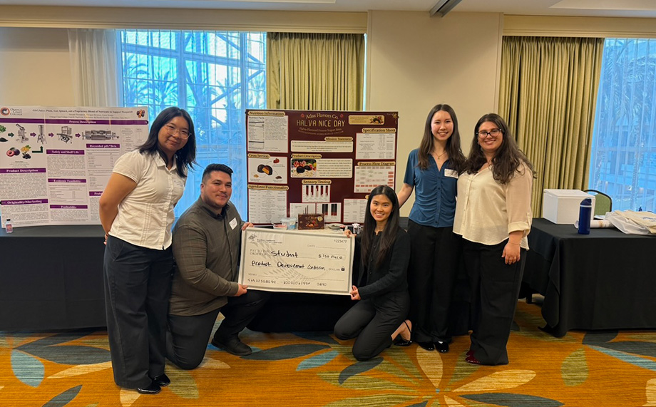 The team poses with a check in front of their poster presentation.