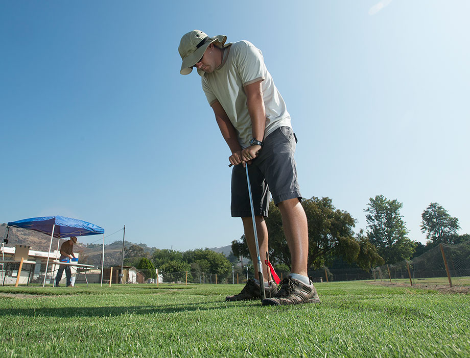 An instructor uses a water probe on a section of turf.