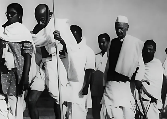 Historic black-and-white photograph of Mahatma Gandhi leading the Salt March in 1930, accompanied by followers including men and women walking together as part of India's nonviolent resistance against British colonial rule.