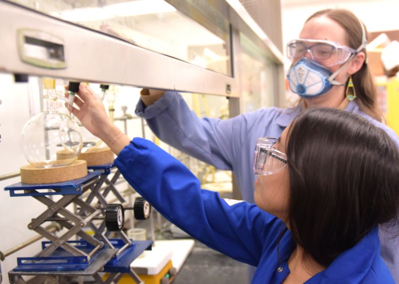 Students wearing lab equipment conduct an experiment.