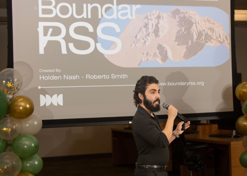 Student holding mic presents to an audience.