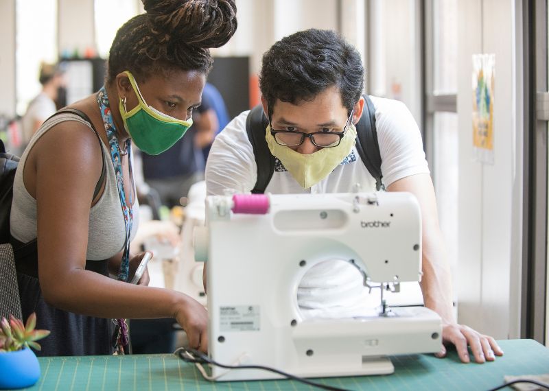 SIIL Ambassador teaches student how to use sewing machine.