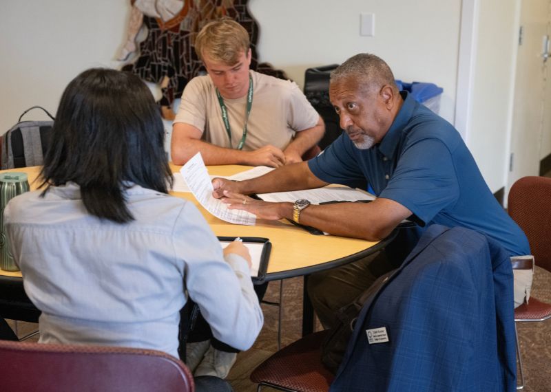 Career counselor holds a resume and listens to student.