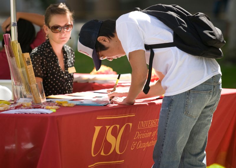 Student signs up at the USC Graduate School table.