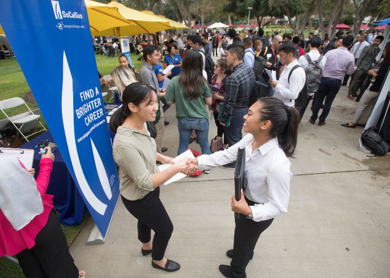 Student shakes hand with recruiter at career fair.