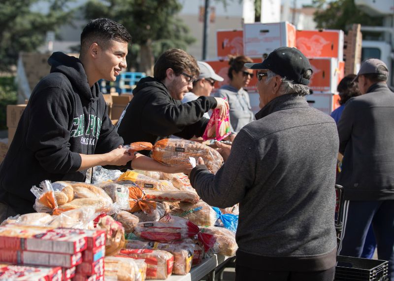 Volunteers distribute fresh bread and food to community members at an outdoor service event.