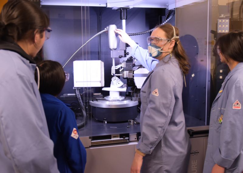 Two students in lab coats and goggles conduct an experiment using pipettes in a science laboratory.