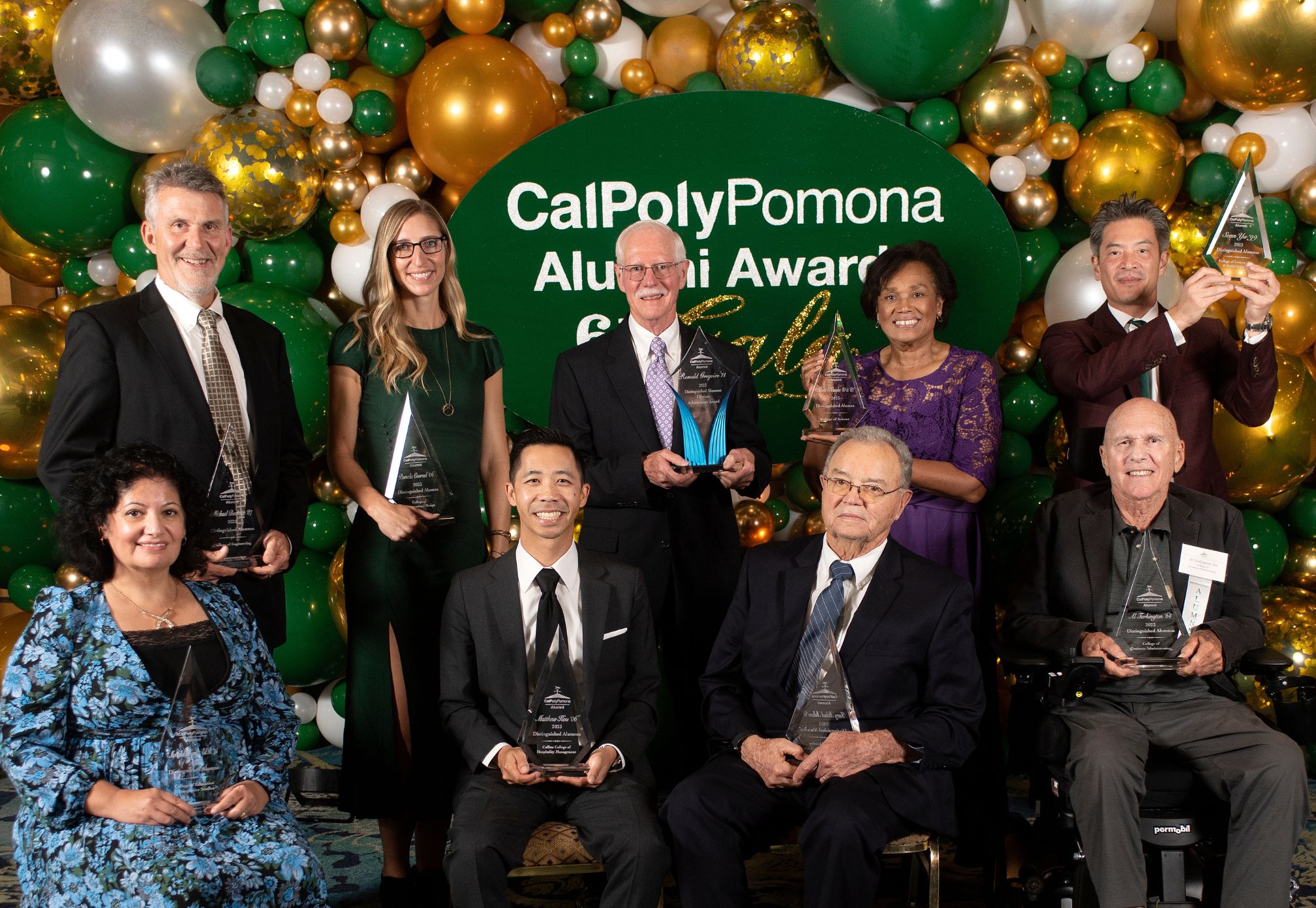 a group of distinguished alumni posing in front of a balloon backdrop