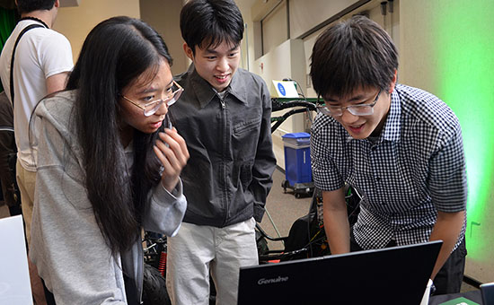 three students looking at a laptop.
