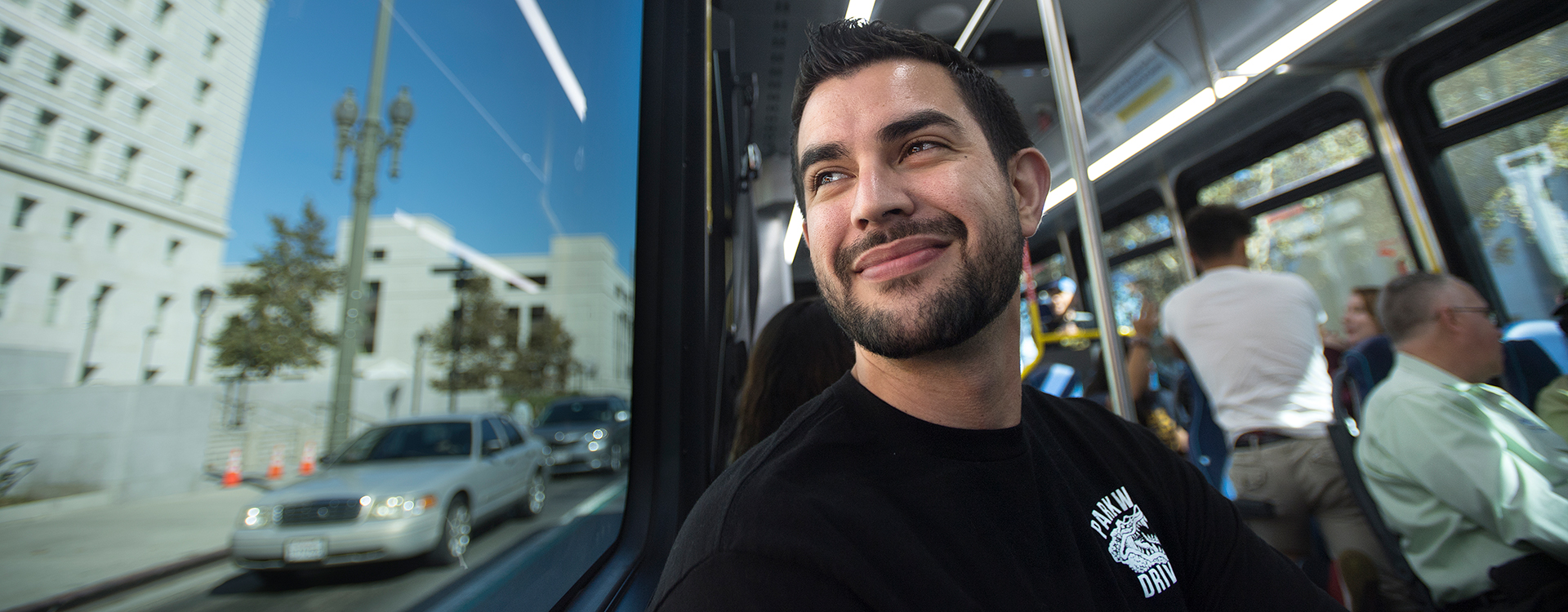 Male smiling looking out the window while on a Foothill Transit bus.