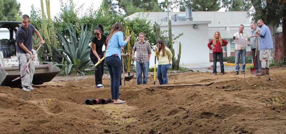 people in a field with shovel about  standing on an empty piece of land