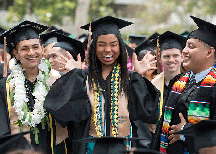 A College of Business Graduate smiles and waves to the crowd during the 2022 commencement ceremonies.