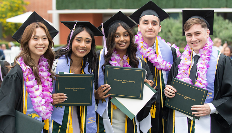Students hold their diplomas and smile during the 2025 commencement ceremonies.