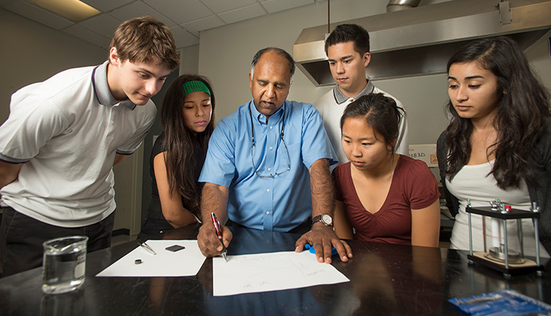 Professor Ravi with students overlook a project. 