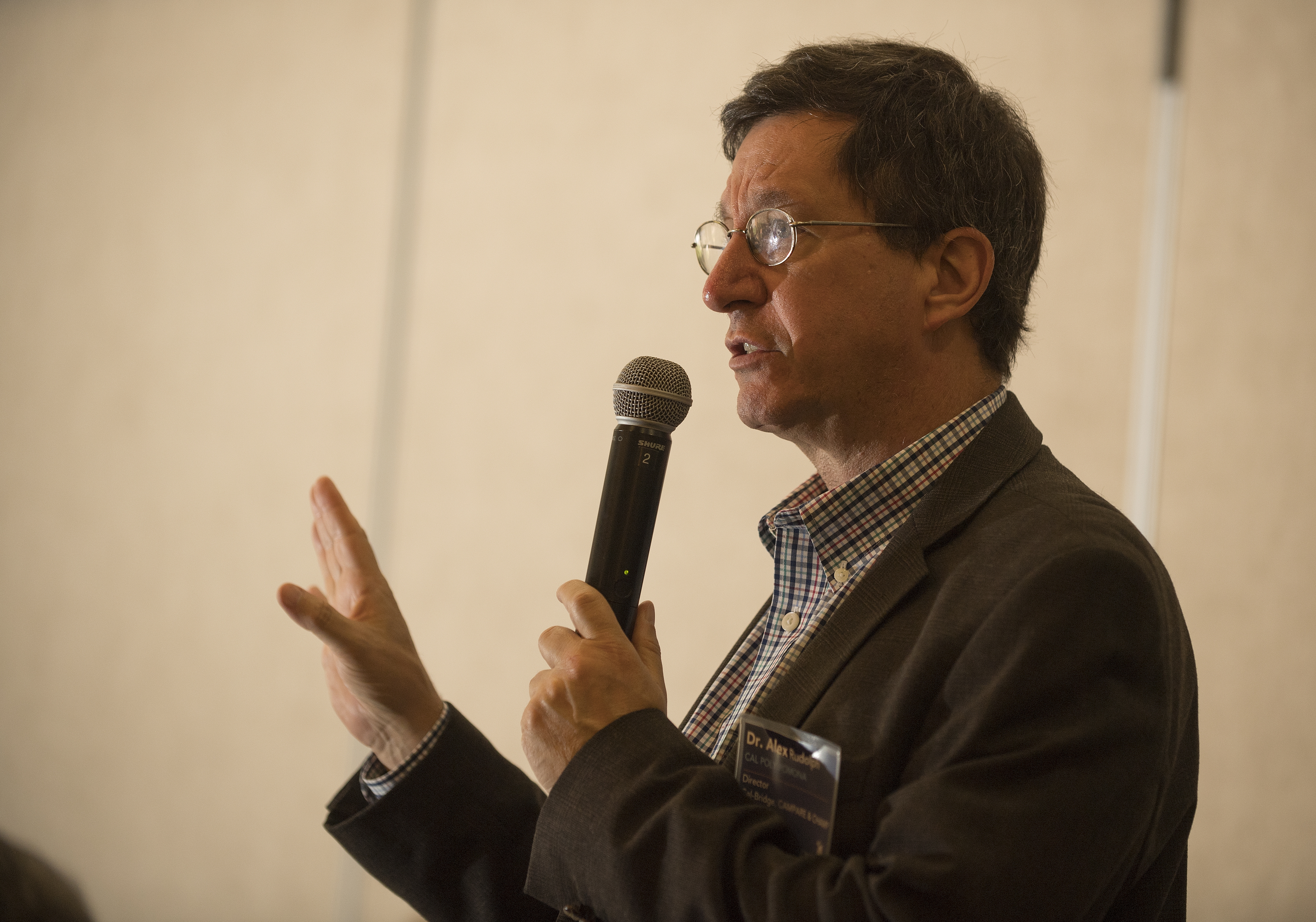 Photo of Cal-Bridge director Alex Rudolph speaking with a microphone in his hand