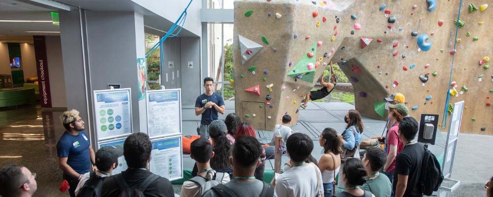 A tour guide talks to transfer students about the climbing wall in the BRIC