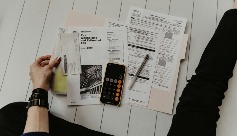 Closeup of calculator and other school items with a had holding paper