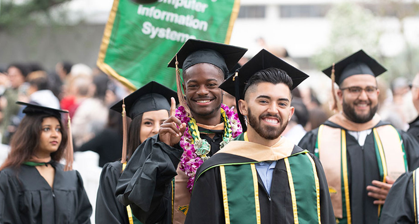 Student holding up number 1 in front of CIS banner at Commencement