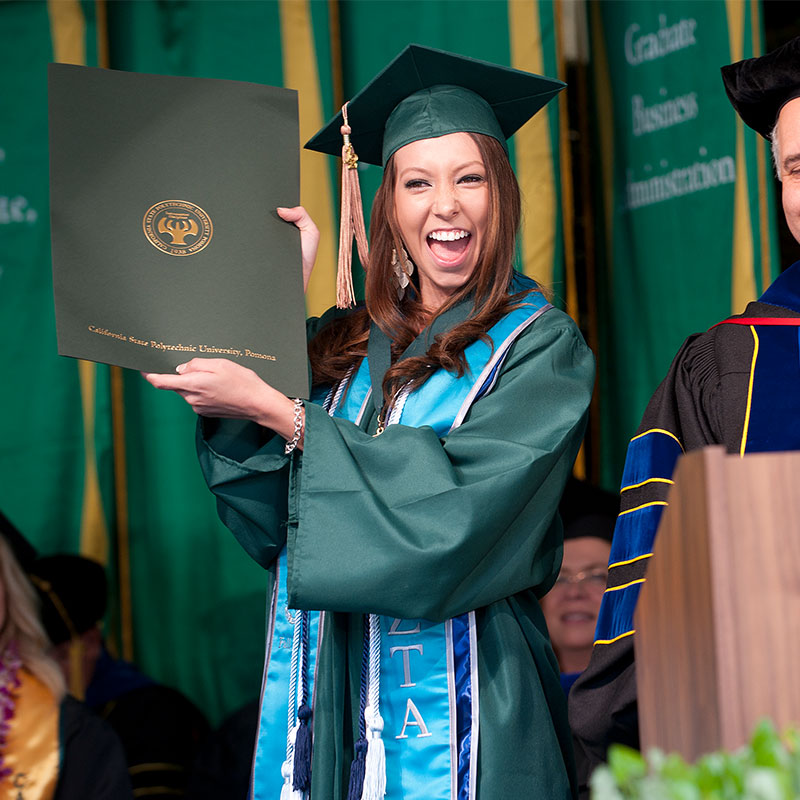 On stage with 2012 McPhee Scholar holding degree during Commencement