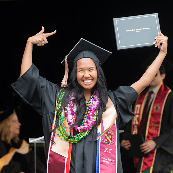 Graduate during commencement holding degree and celebrating