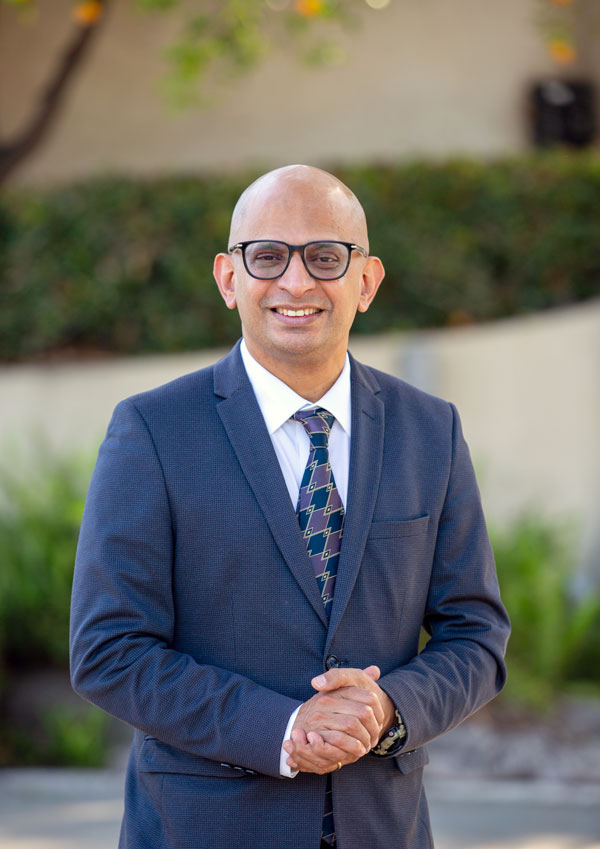 CBA Singelyn Family Dean Sandeep Krishnamurthy poses in front of building