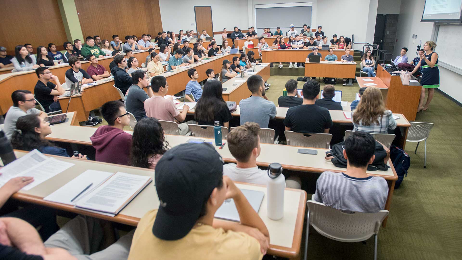 Female MHR professor teaching packed class on first day of class