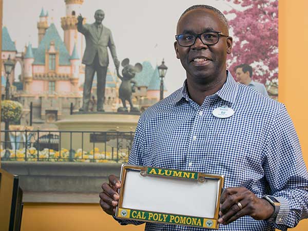 CBA Alumni Chapter president at work at Disneyland holding alumni license plate frame