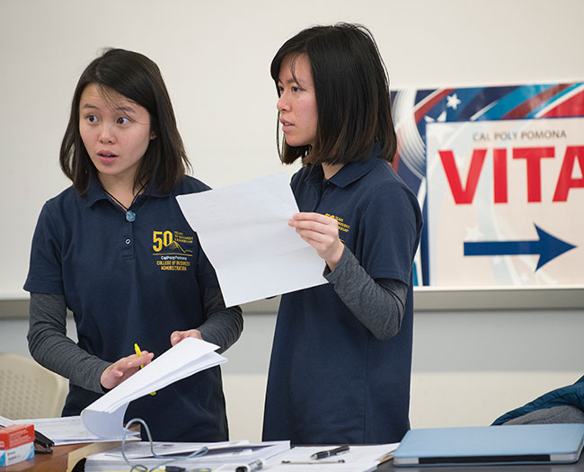 Two female students checking in guests at VITA event