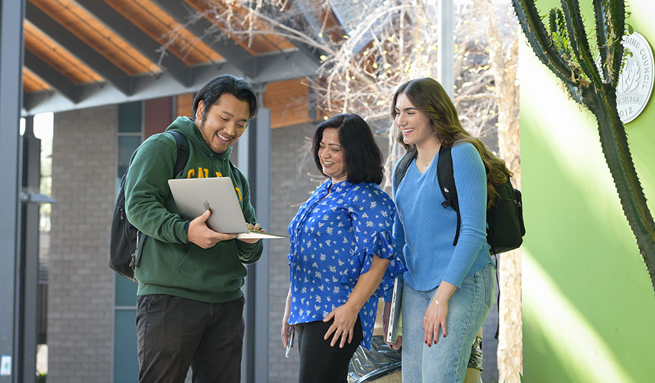 Students showing professor laptop in CBA courtyard