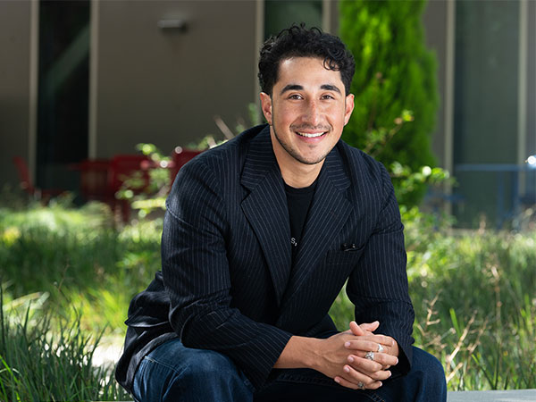 Johan Acosta sitting on a bench in the CBA courtyard
