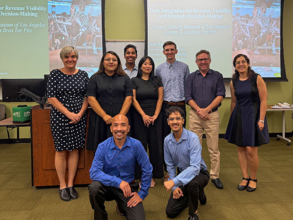 Students and professor gather in front of presentation screens showing data findings