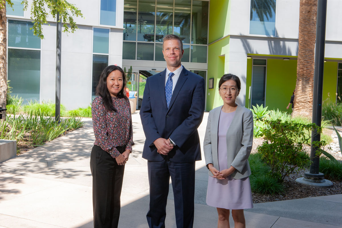 Three new CBA faculty posing in front of building