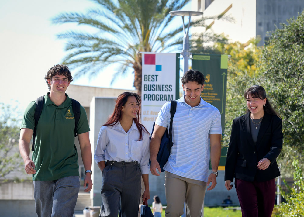 Four students talking while walking toward the CBA complex