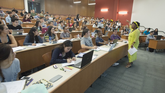 Professor smiling while speaking to students in a large lecture hall