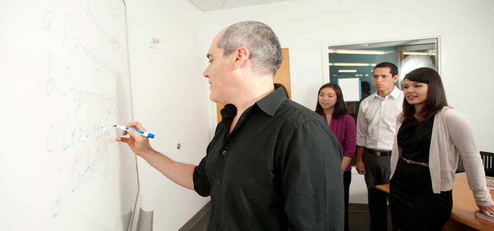 Instructor writing something on whiteboard with participants watching