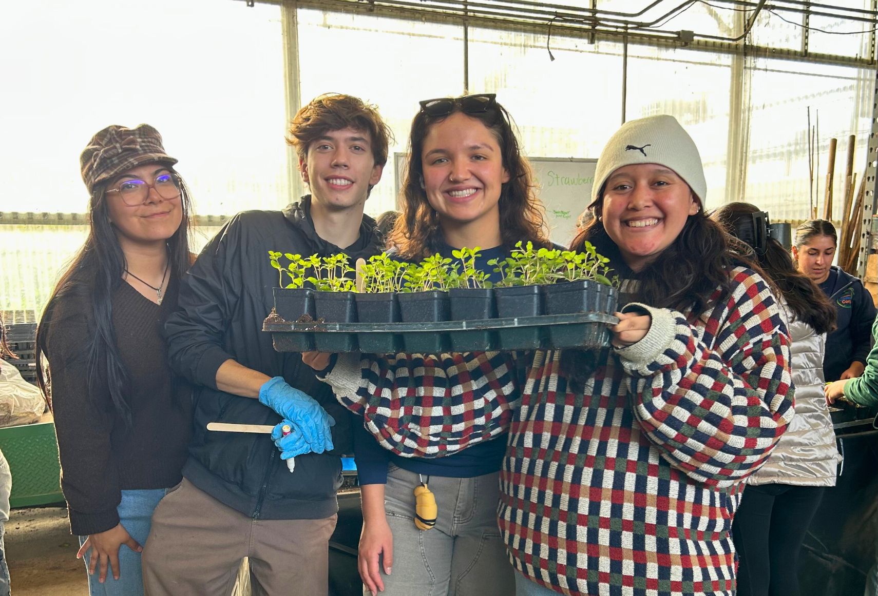 students holding a plant as they take a photo