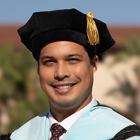 Male student in Tam and is smiling. 