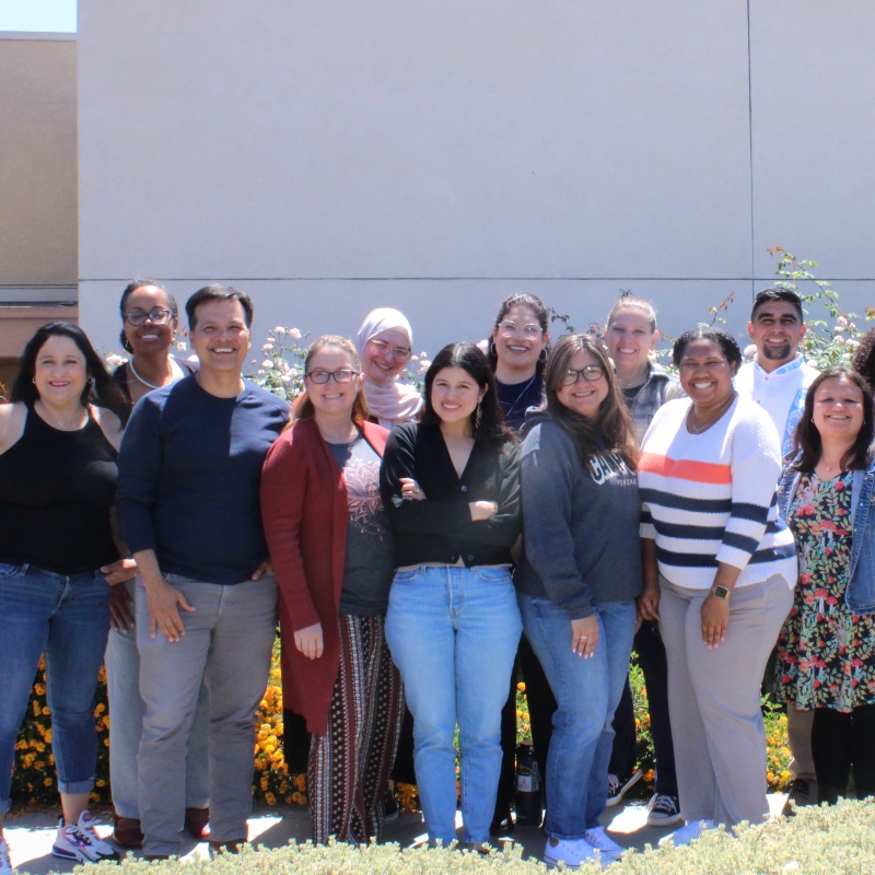 Groups of students outside next to a classroom smiling and standing for a photo. 