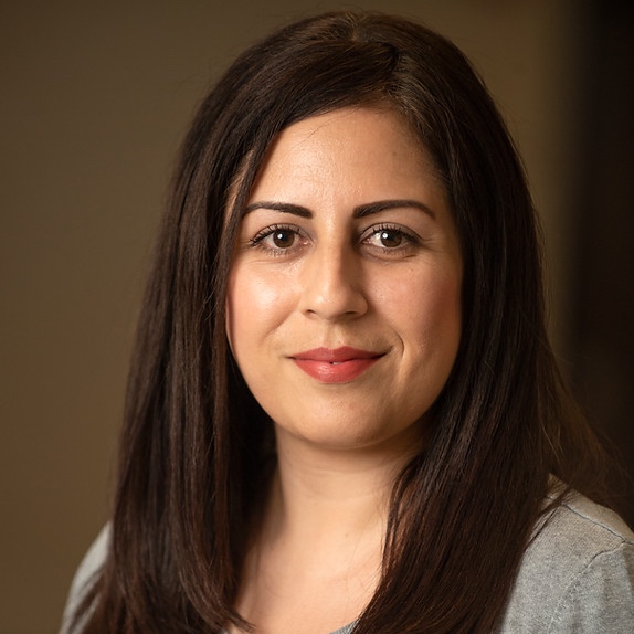 Photo of female smiling with brown long hair that is straight with pink lips.